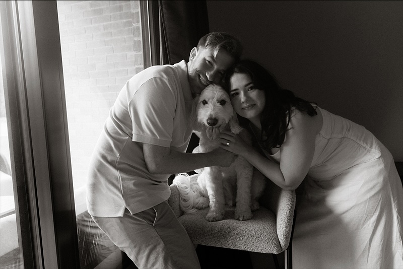Kaylee and David leaning in around Monty on a chair by the window