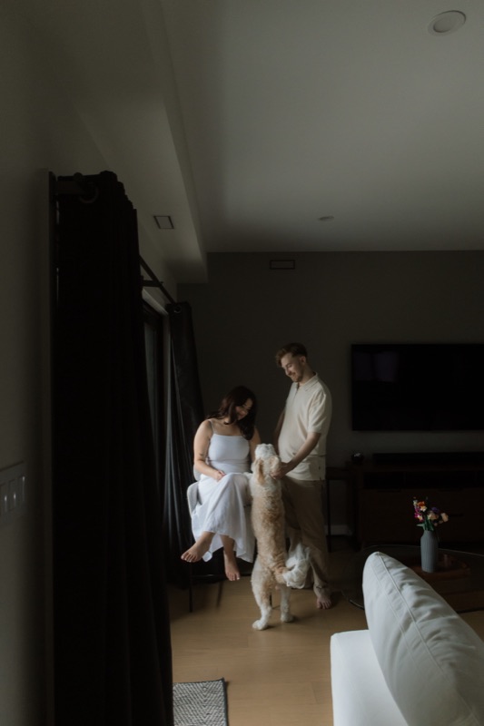 Kaylee and David at home with Monty, soft evening light through a doorway