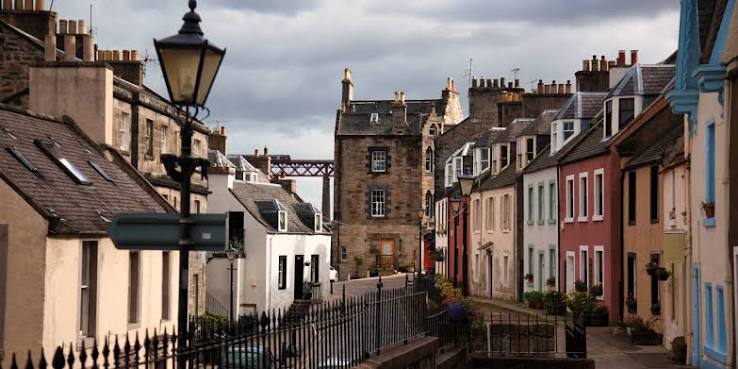 A lane of painted houses in South Queensferry, with the Forth Bridge beyond